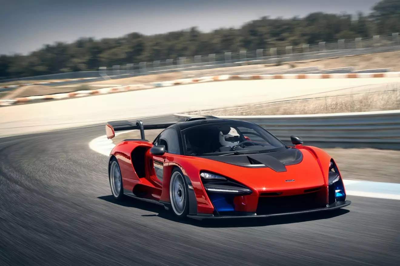 High performance McLaren Senna road car on a track, showing its immense carbon fiber rear wing and low-slung body.